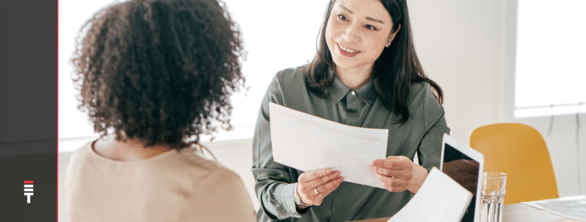 Two women discussing hiring metrics in an office setting.